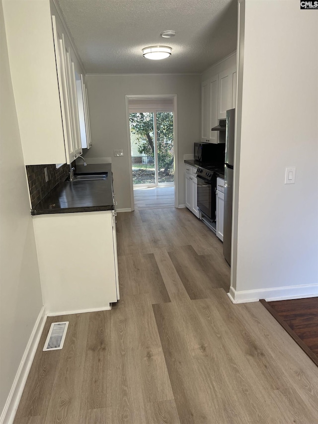 kitchen featuring sink, white cabinetry, black appliances, a textured ceiling, and light wood-type flooring