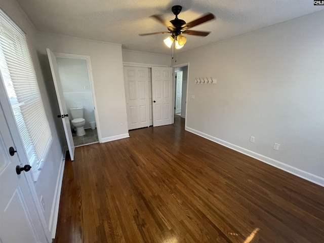 unfurnished bedroom with ceiling fan, ensuite bathroom, dark hardwood / wood-style flooring, and a closet