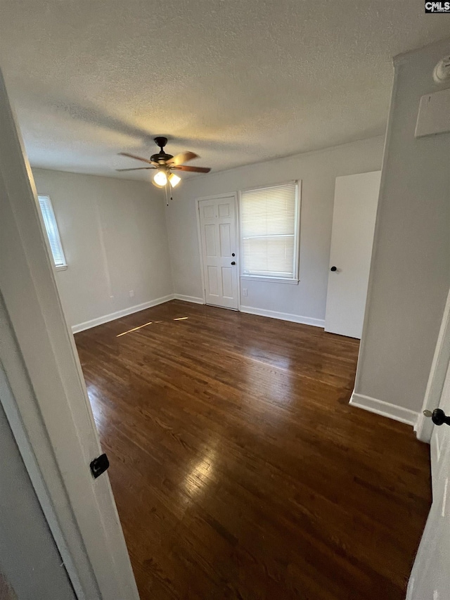 empty room with dark hardwood / wood-style flooring, a textured ceiling, and ceiling fan