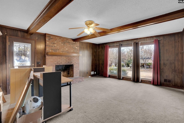 living room with beamed ceiling, a textured ceiling, and wood walls