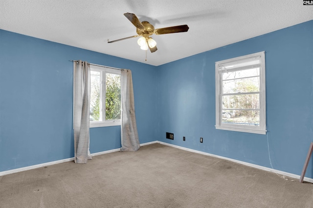 carpeted spare room featuring ceiling fan and a textured ceiling