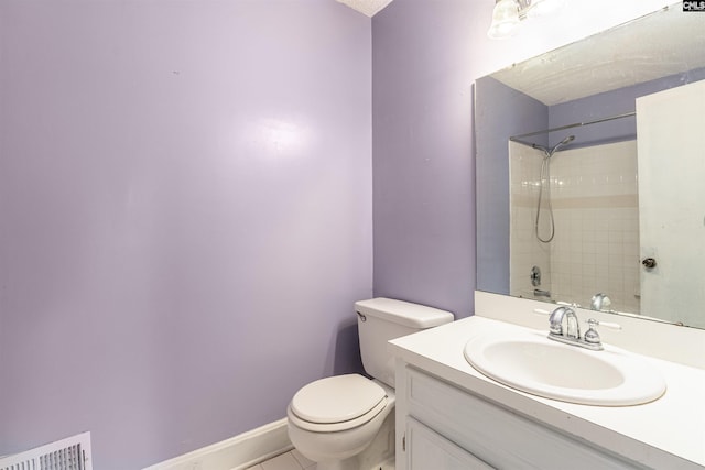 bathroom featuring vanity, tiled shower, and toilet