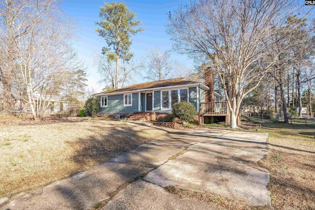 ranch-style home featuring a deck and a front lawn