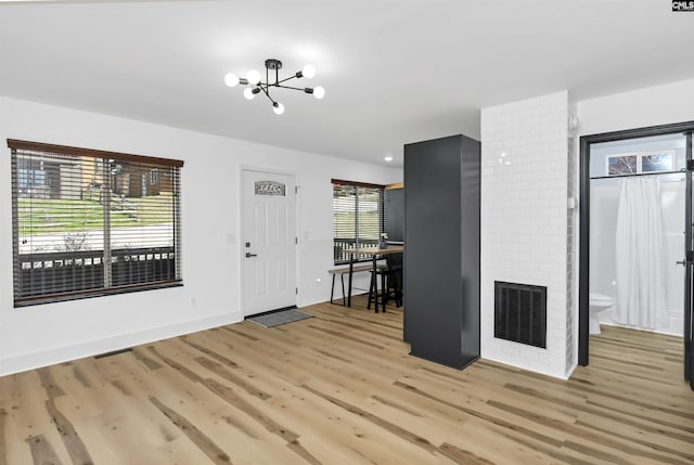 entryway featuring a fireplace, a notable chandelier, and light hardwood / wood-style flooring