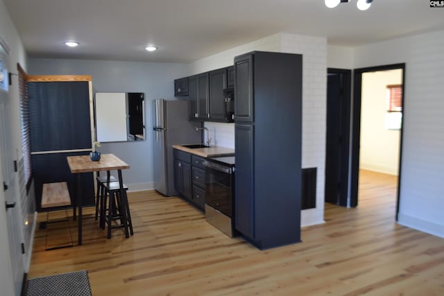 kitchen featuring sink, decorative backsplash, stainless steel appliances, and light hardwood / wood-style floors