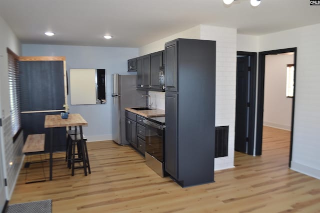 kitchen with sink, stainless steel appliances, and light hardwood / wood-style floors