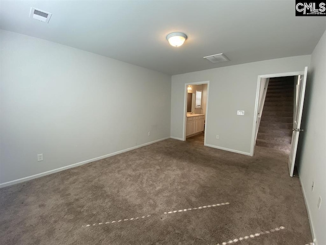 unfurnished bedroom with connected bathroom and dark carpet