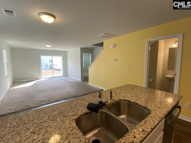 kitchen with dark colored carpet, light stone countertops, and sink