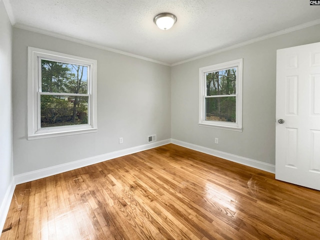 unfurnished room featuring plenty of natural light, crown molding, baseboards, and wood finished floors