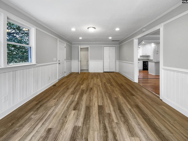 interior space featuring dark wood-type flooring, wainscoting, recessed lighting, and crown molding