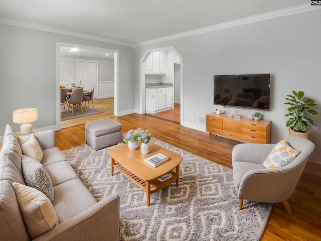 living room with baseboards, light wood finished floors, and crown molding