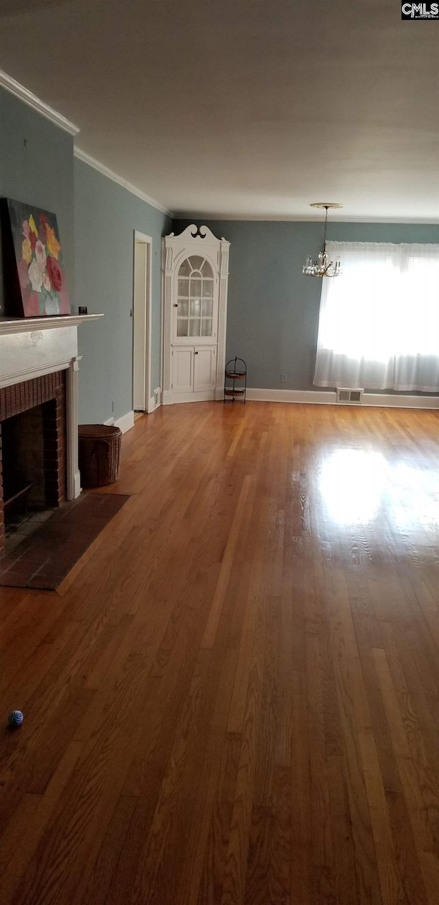 unfurnished living room featuring a fireplace, wood finished floors, visible vents, baseboards, and crown molding