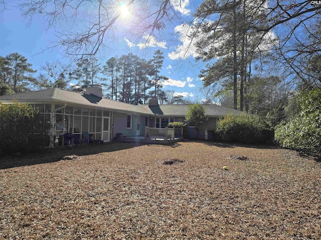 back of house with a sunroom and a chimney