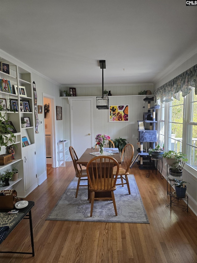 dining space with ornamental molding, built in features, and wood finished floors