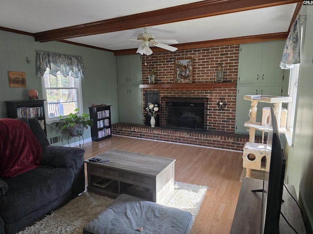 living room featuring light wood-type flooring, beam ceiling, visible vents, and a fireplace