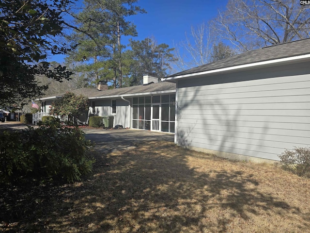 view of side of property featuring a sunroom and a chimney