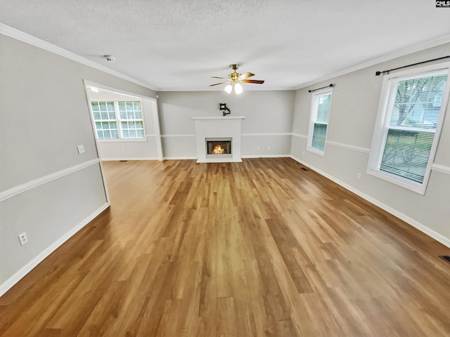 unfurnished living room with crown molding, a healthy amount of sunlight, a textured ceiling, and light hardwood / wood-style floors