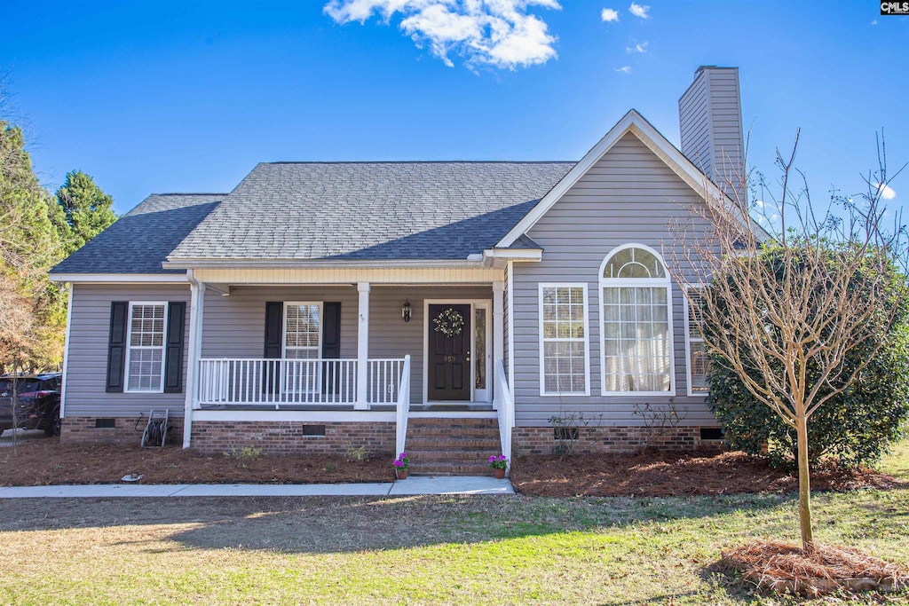 ranch-style house featuring covered porch and a front lawn