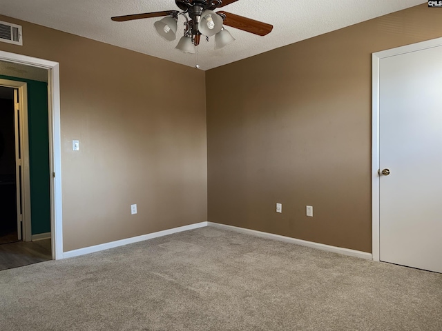 empty room featuring ceiling fan, light colored carpet, and a textured ceiling