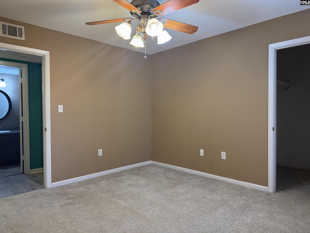 unfurnished bedroom with a walk in closet, light carpet, ceiling fan, and a closet