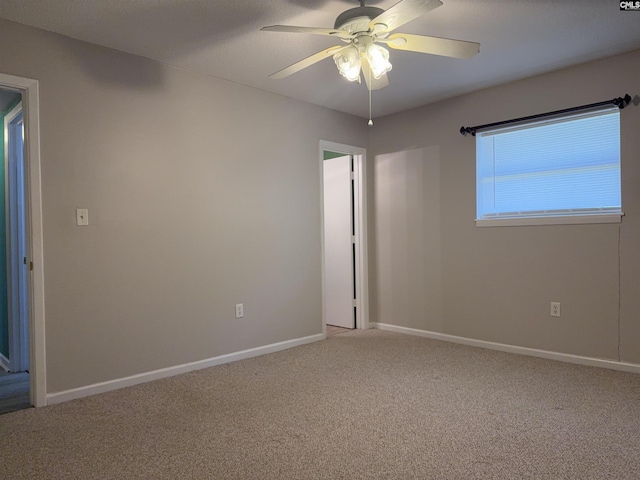 carpeted spare room featuring ceiling fan