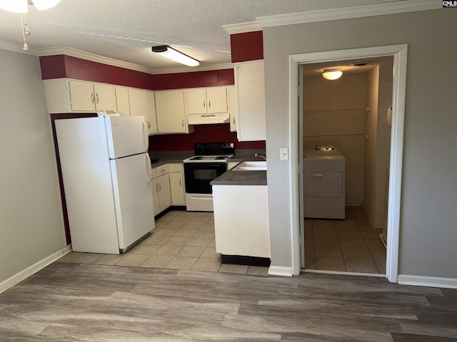 kitchen with white refrigerator, washer / dryer, electric range oven, and white cabinets