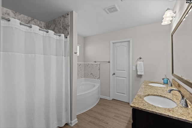 bathroom featuring vanity, hardwood / wood-style floors, and a tub to relax in