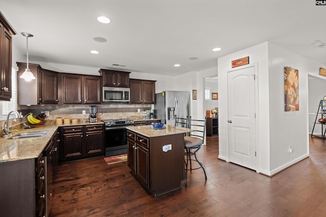 kitchen with dark wood-type flooring, sink, decorative light fixtures, a kitchen island, and stainless steel appliances