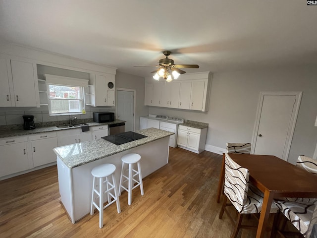 3442 Blossom St, Columbia, SC 29205 - kitchen featuring sink, white cabinetry, washing machine and dryer, a center island, and black appliances