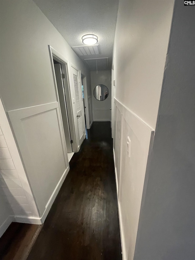 corridor featuring dark wood-type flooring and a textured ceiling