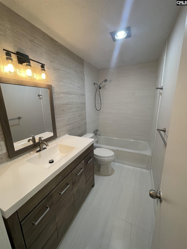 full bathroom featuring tiled shower / bath combo, vanity, a textured ceiling, and toilet