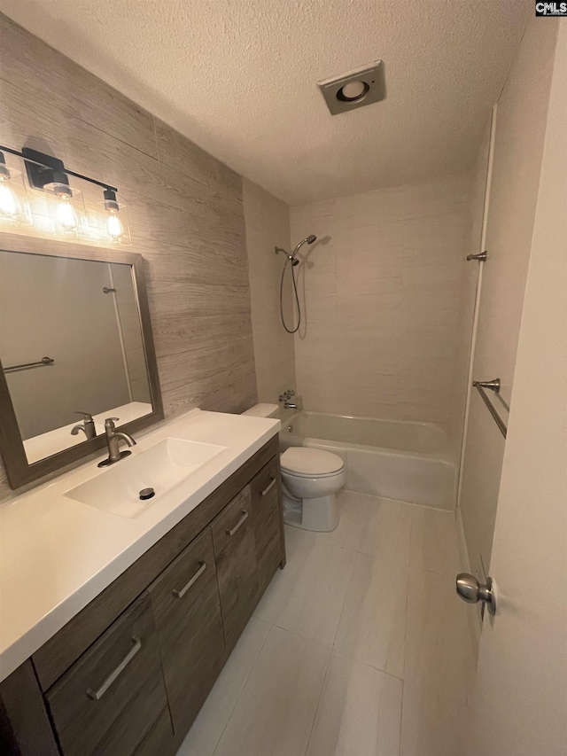 full bathroom featuring vanity, toilet, tiled shower / bath combo, and a textured ceiling