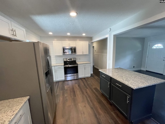 kitchen with stainless steel appliances, dark wood-type flooring, white cabinets, and a textured ceiling