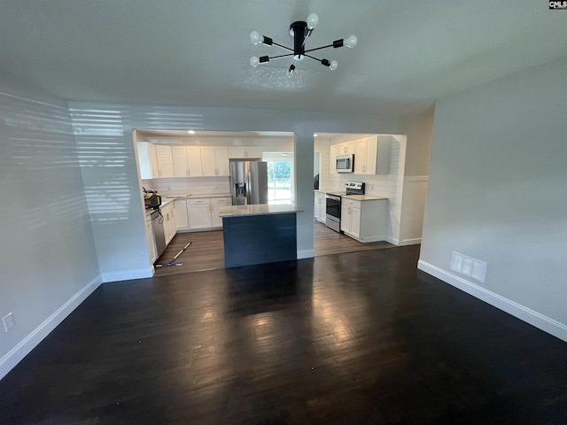 kitchen featuring appliances with stainless steel finishes, white cabinetry, tasteful backsplash, a kitchen island, and dark hardwood / wood-style flooring