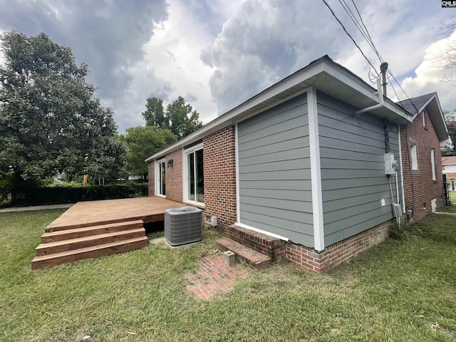 view of side of home featuring central AC unit, a lawn, and a deck