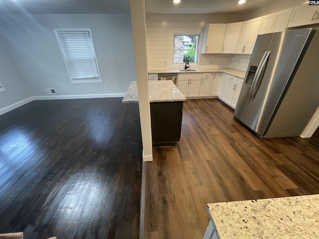 kitchen featuring sink, white cabinets, dark hardwood / wood-style flooring, stainless steel fridge, and light stone counters