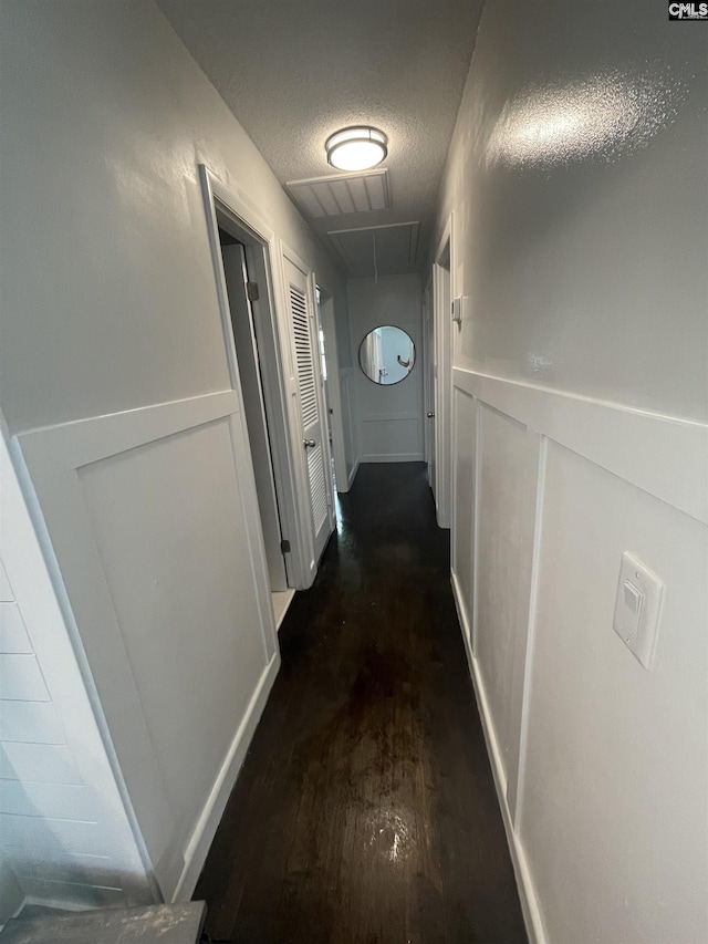 hall with dark wood-type flooring and a textured ceiling