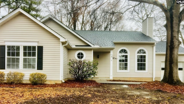 ranch-style home with a garage, a shingled roof, and a chimney