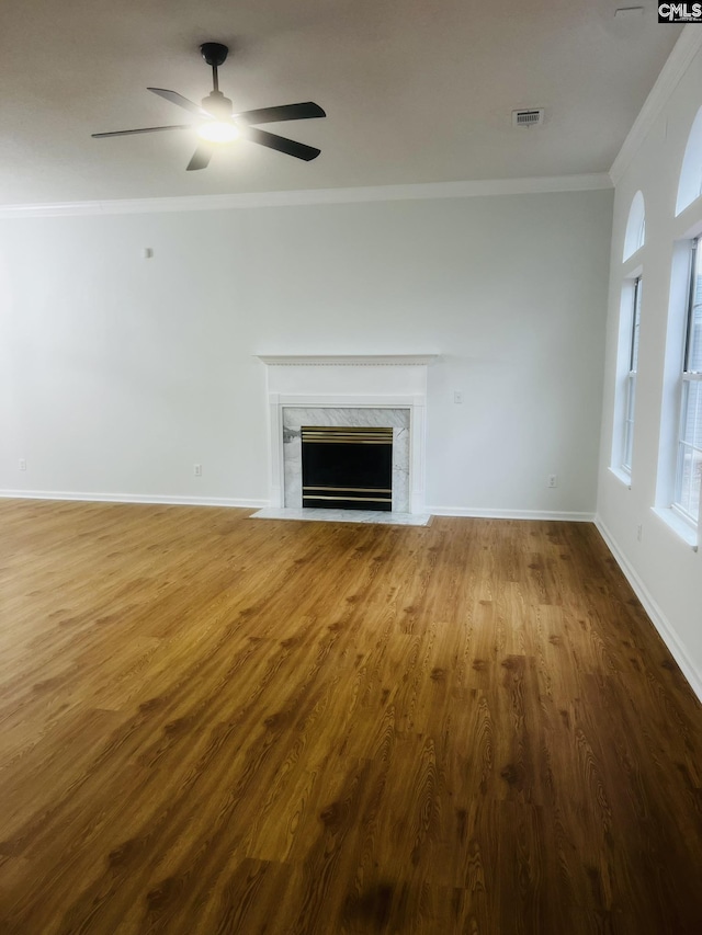 unfurnished living room featuring a premium fireplace, wood finished floors, visible vents, and crown molding