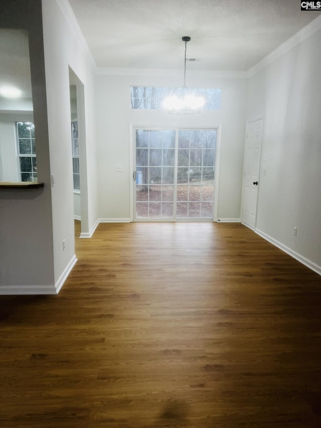 unfurnished dining area with baseboards, a notable chandelier, ornamental molding, and wood finished floors