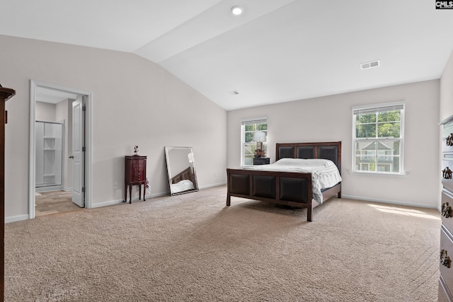 carpeted bedroom featuring multiple windows, lofted ceiling, and connected bathroom