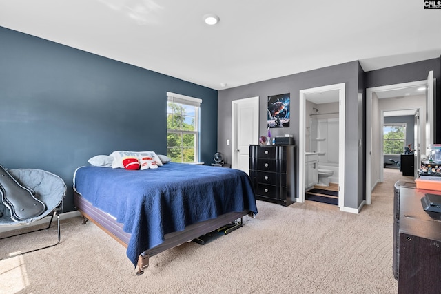 bedroom with multiple windows, light colored carpet, and ensuite bathroom