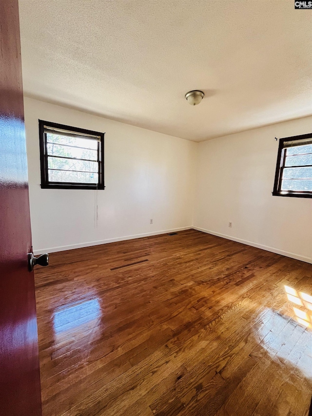 empty room with dark wood-type flooring and a textured ceiling