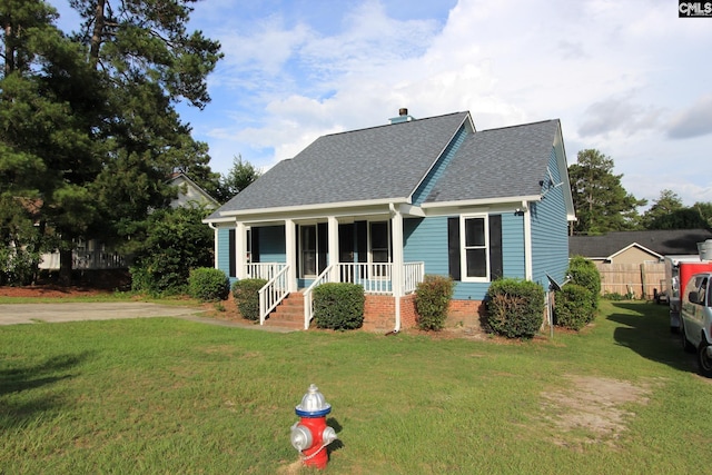 view of front of home featuring a front yard, fence, covered porch, and a shingled roof