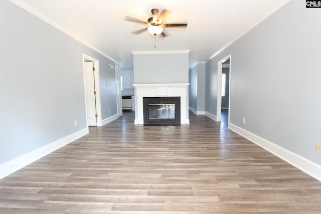 unfurnished living room featuring a glass covered fireplace, wood finished floors, a ceiling fan, and baseboards