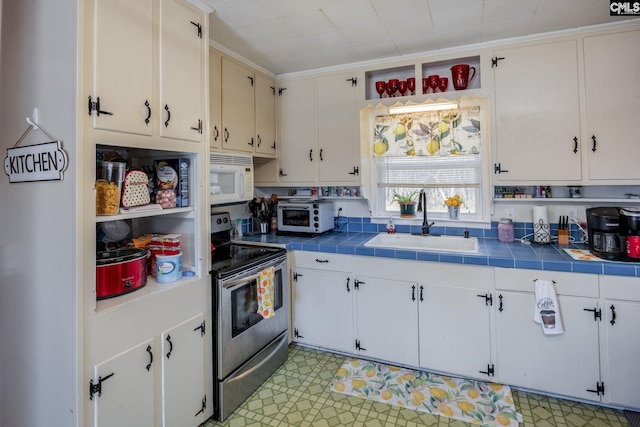 kitchen with stainless steel electric range, white cabinetry, tile counters, and sink