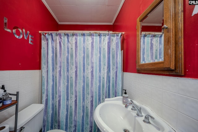 bathroom with crown molding, tile walls, toilet, and sink