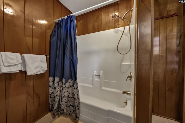 bathroom with wood walls and shower / tub combo