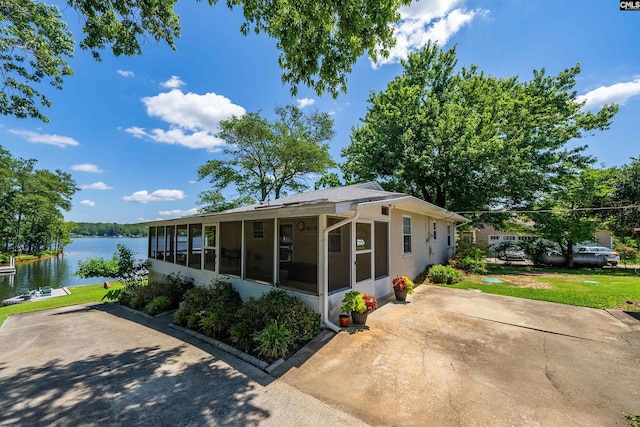 view of front facade featuring a front yard, a sunroom, and a water view