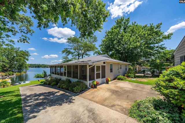 view of front of home with a water view, a front yard, and a sunroom